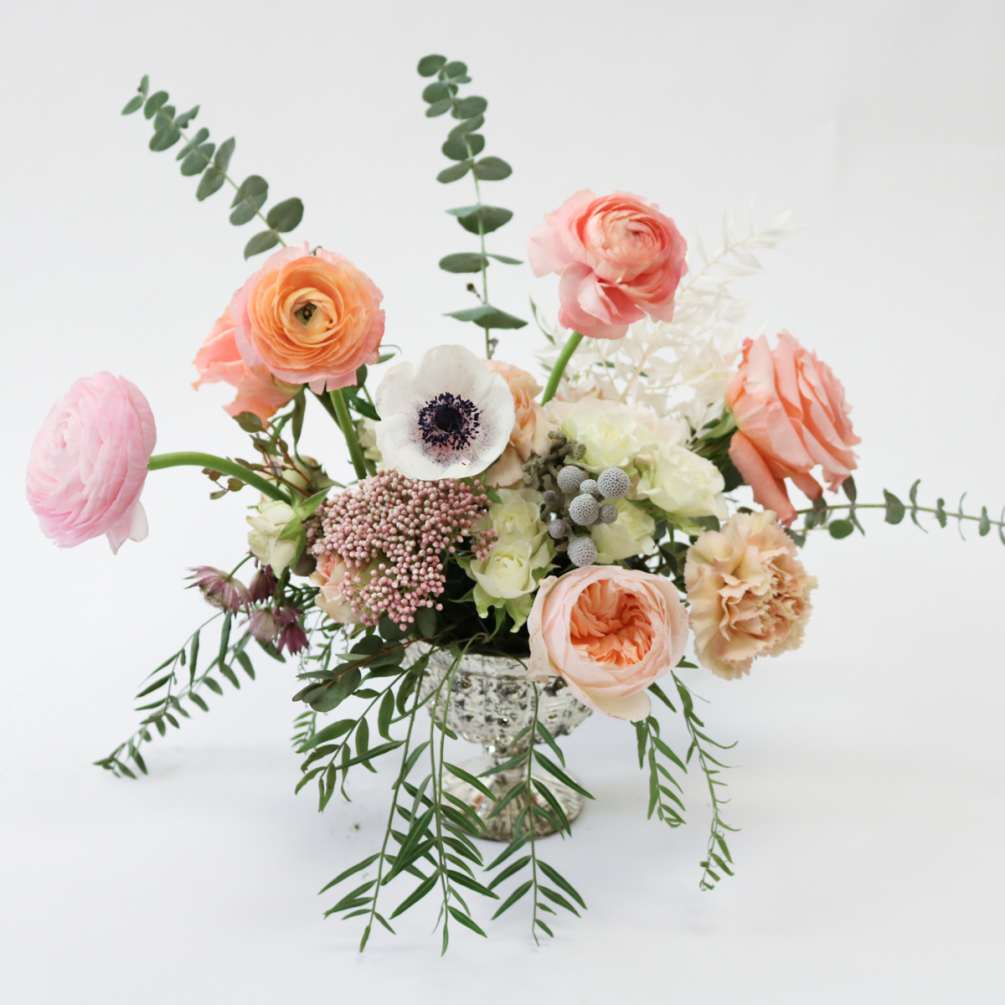 A stunning display of garden-style beauty, featuring delicate peach ranunculus and garden