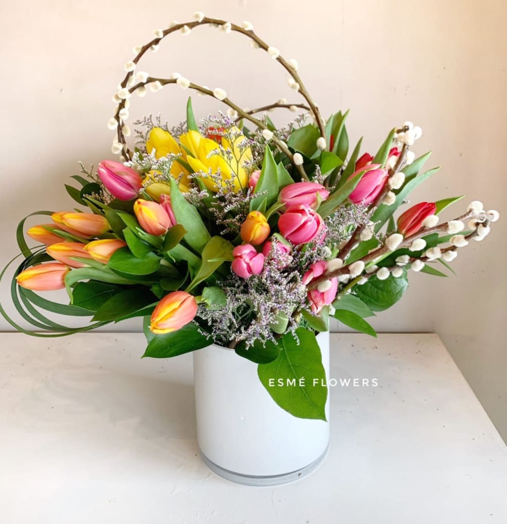 An arrangement of roughly 50 assorted tulips, accented with willow branches and