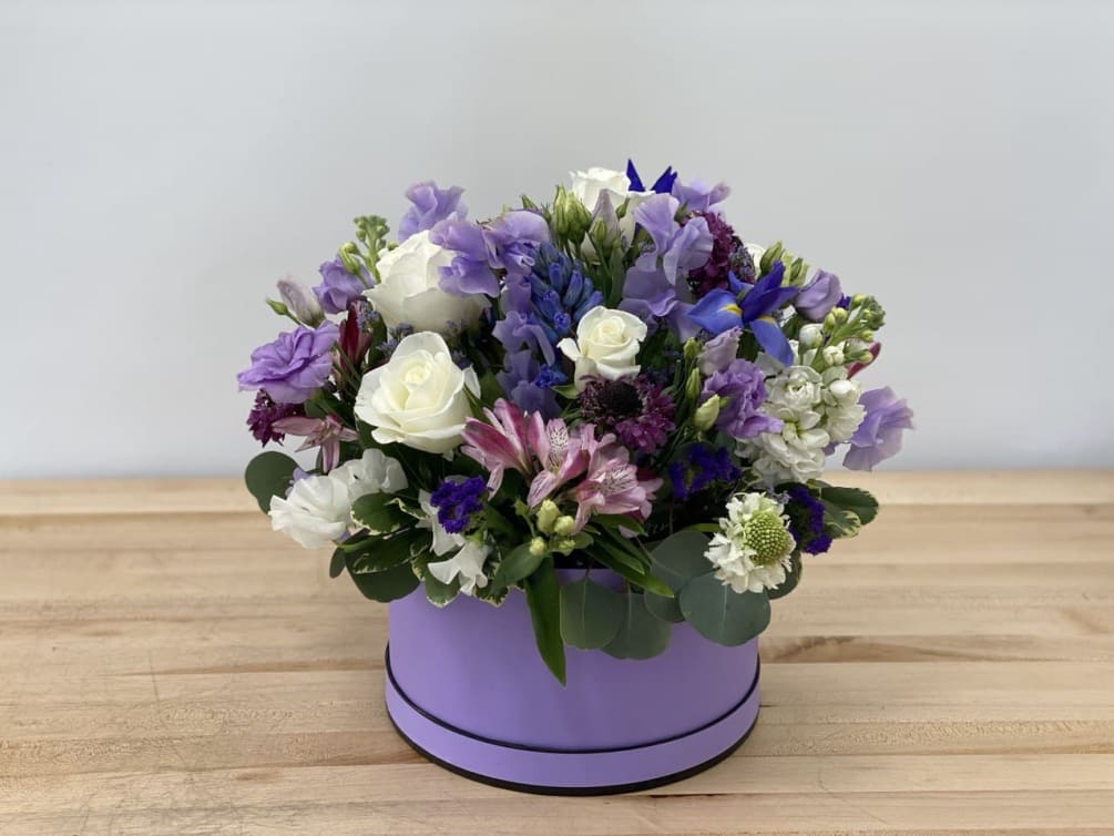 A combination of white roses, lavender lisianthus, sweet peas, and iris in