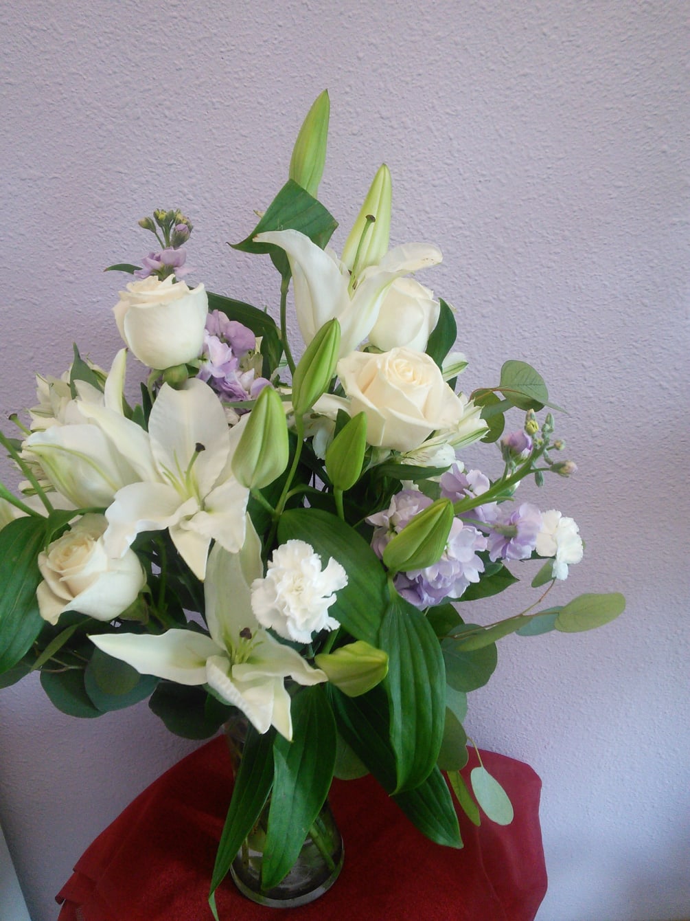 White roses, white lilies and lavender stock. 
Medium size clear vase full
