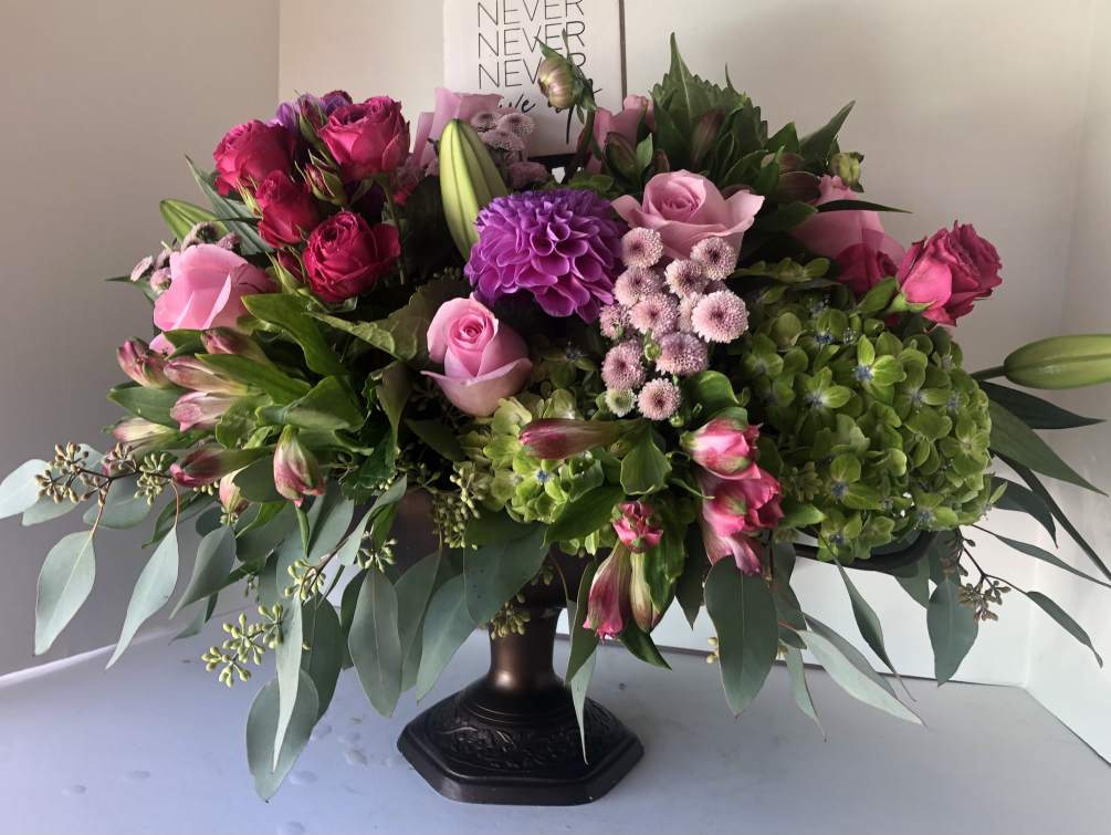 An arrangement of seasonal blooms in a custom vase. Add is a