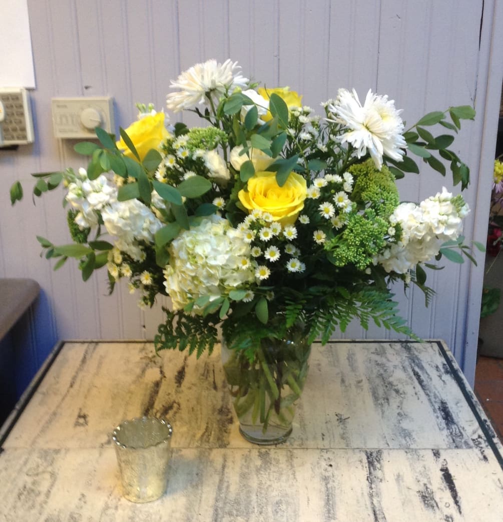 This lush vase features blue hydrangea, lemon lime roses and white stock.