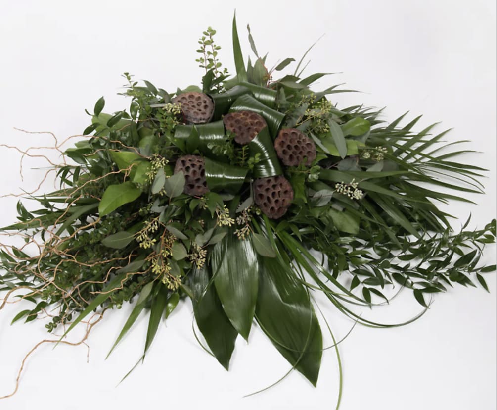 Casket Spray Tribute of lush greens and organic accents.