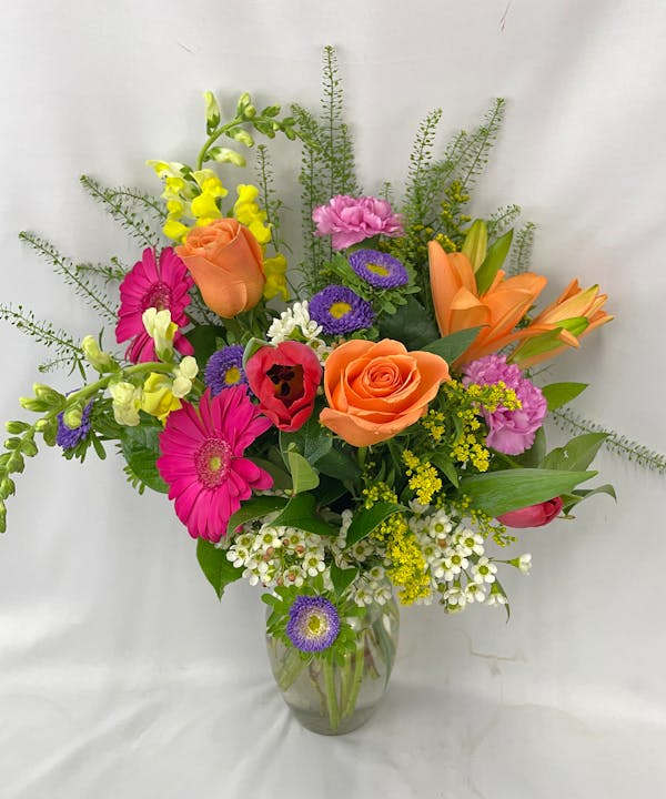 This exceptional arrangement of red, yellow, hot pink and purple flowers will