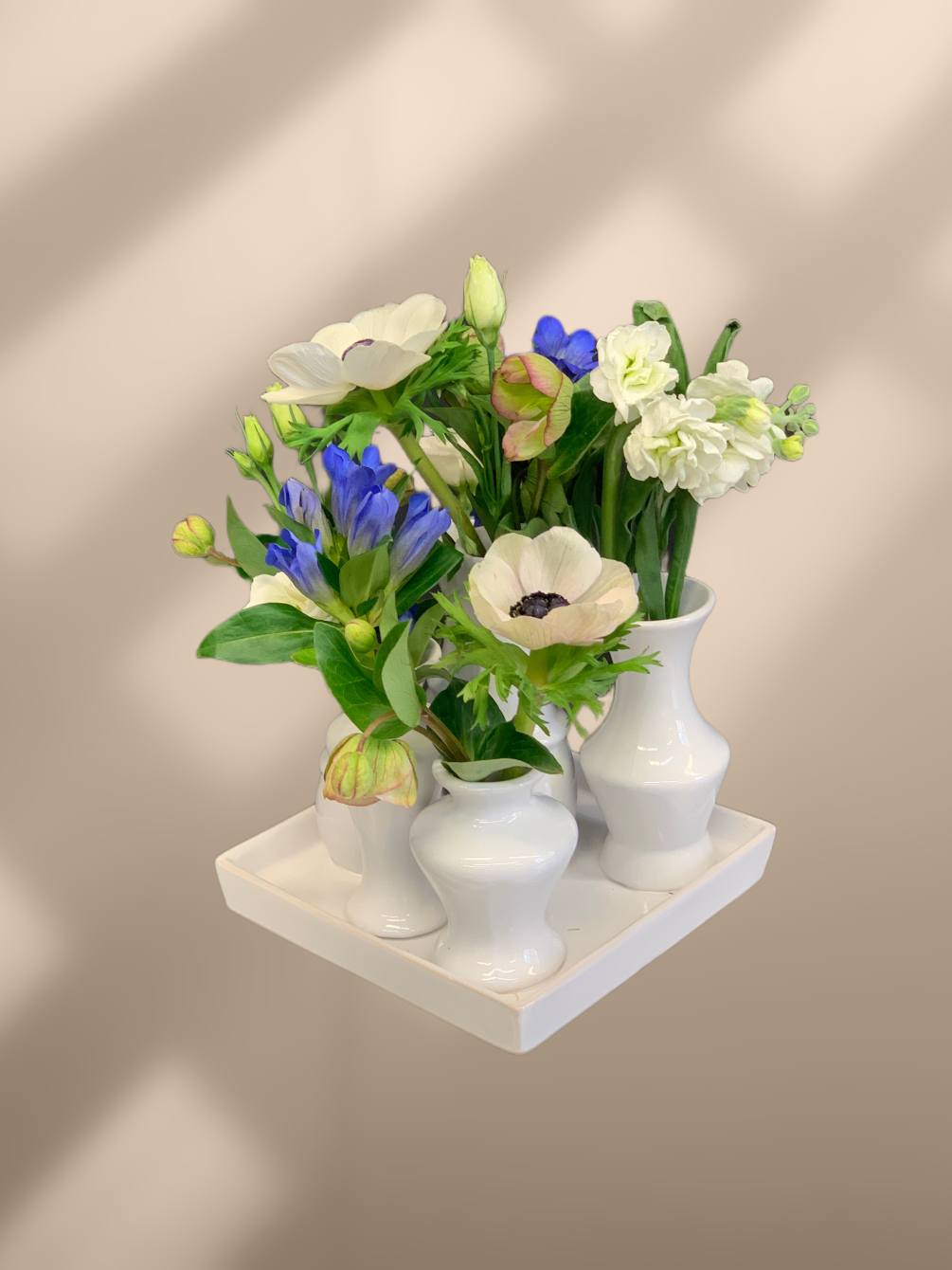 A collection of bud vases with blue and white flowers