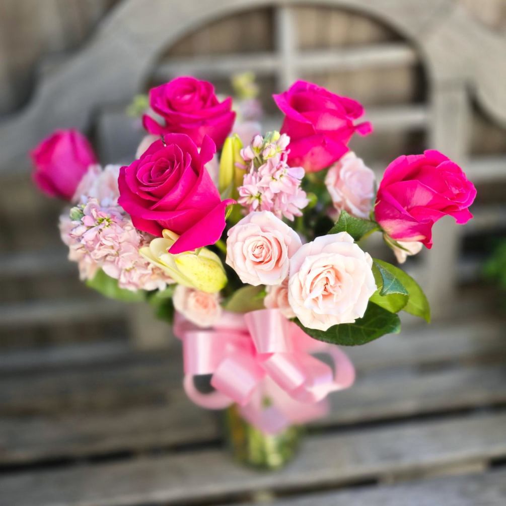 This arrangement features hot pink roses and light pink supporting florals including