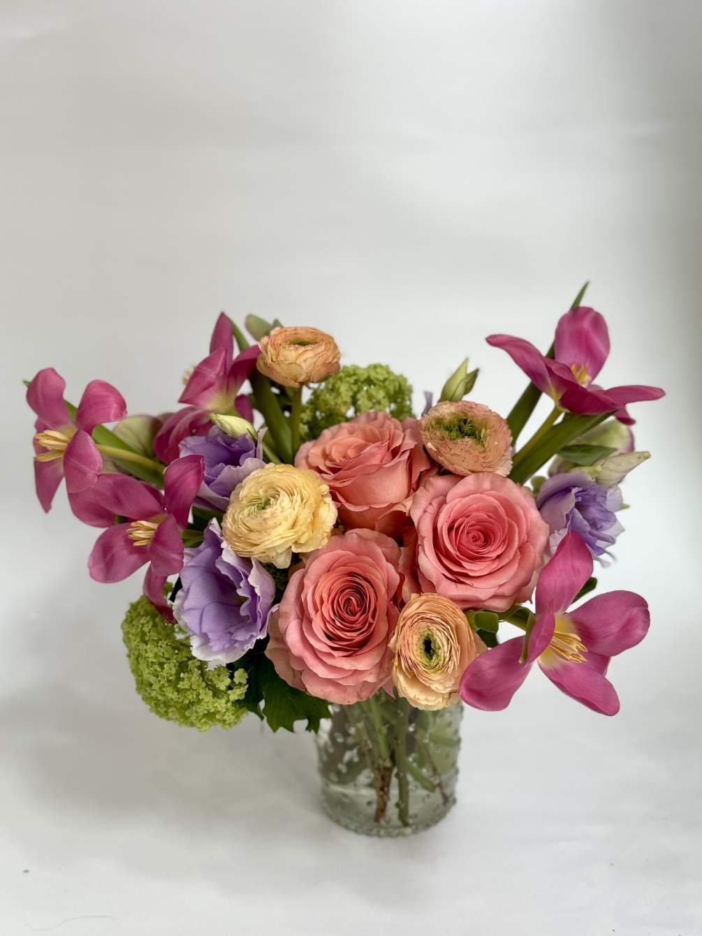 Whimsical and fun spring floral piece in a glass vase.