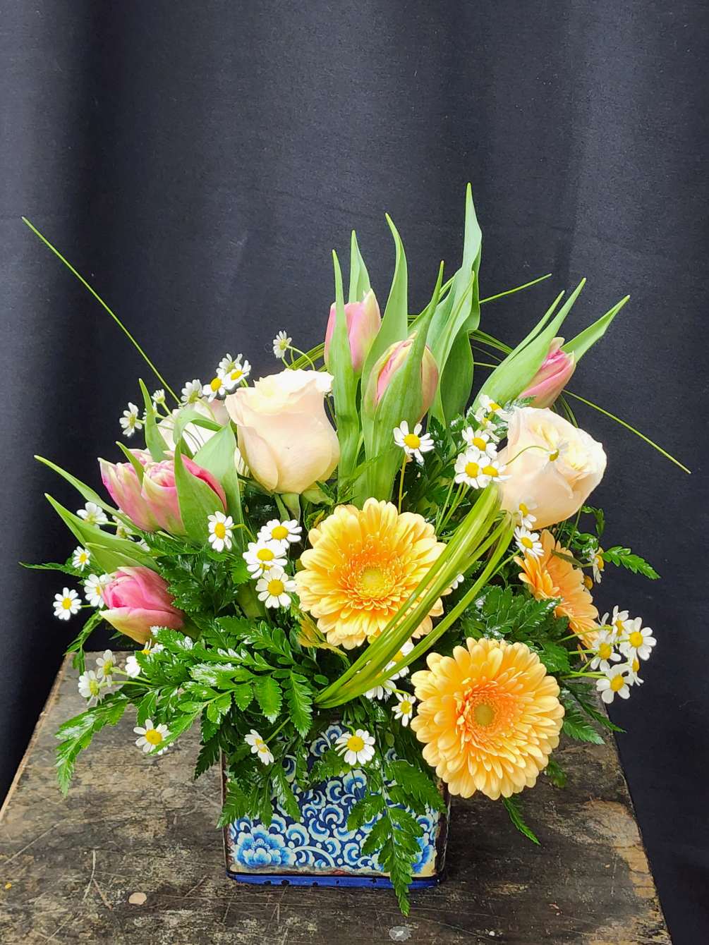 Ceramic container with gorgeous tulips, beautiful gerbera daisies and stunning roses. This