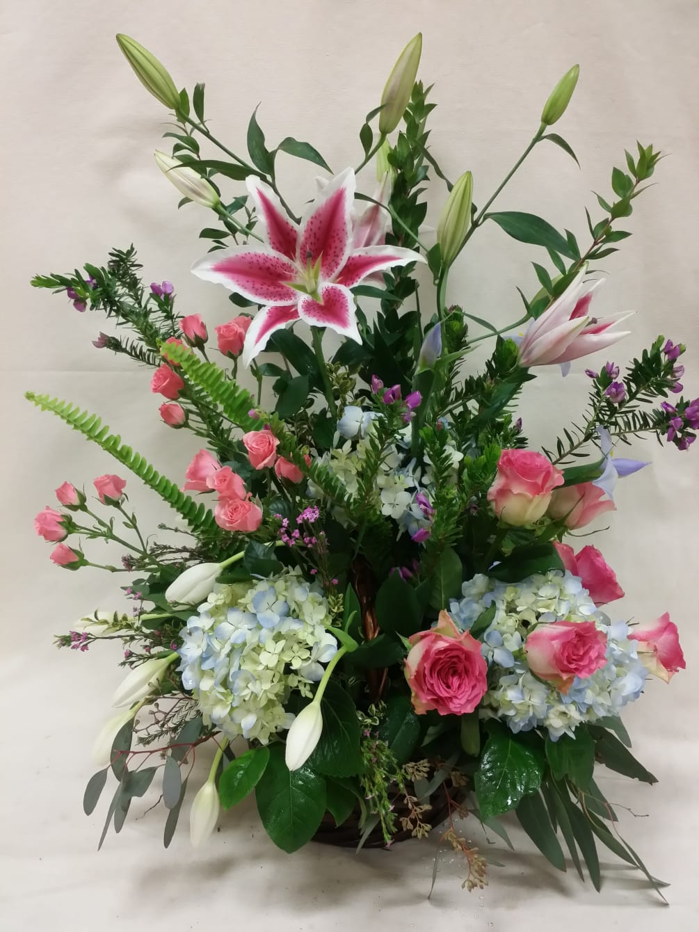 Stargazer lilies, blue hydrangea, and pink roses all displayed in a very