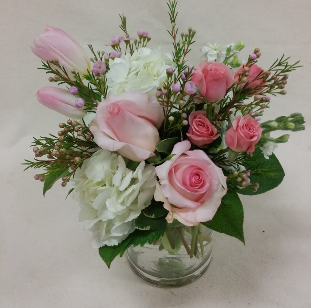 Pastel pink roses and spray roses are arranged with blush tulips and