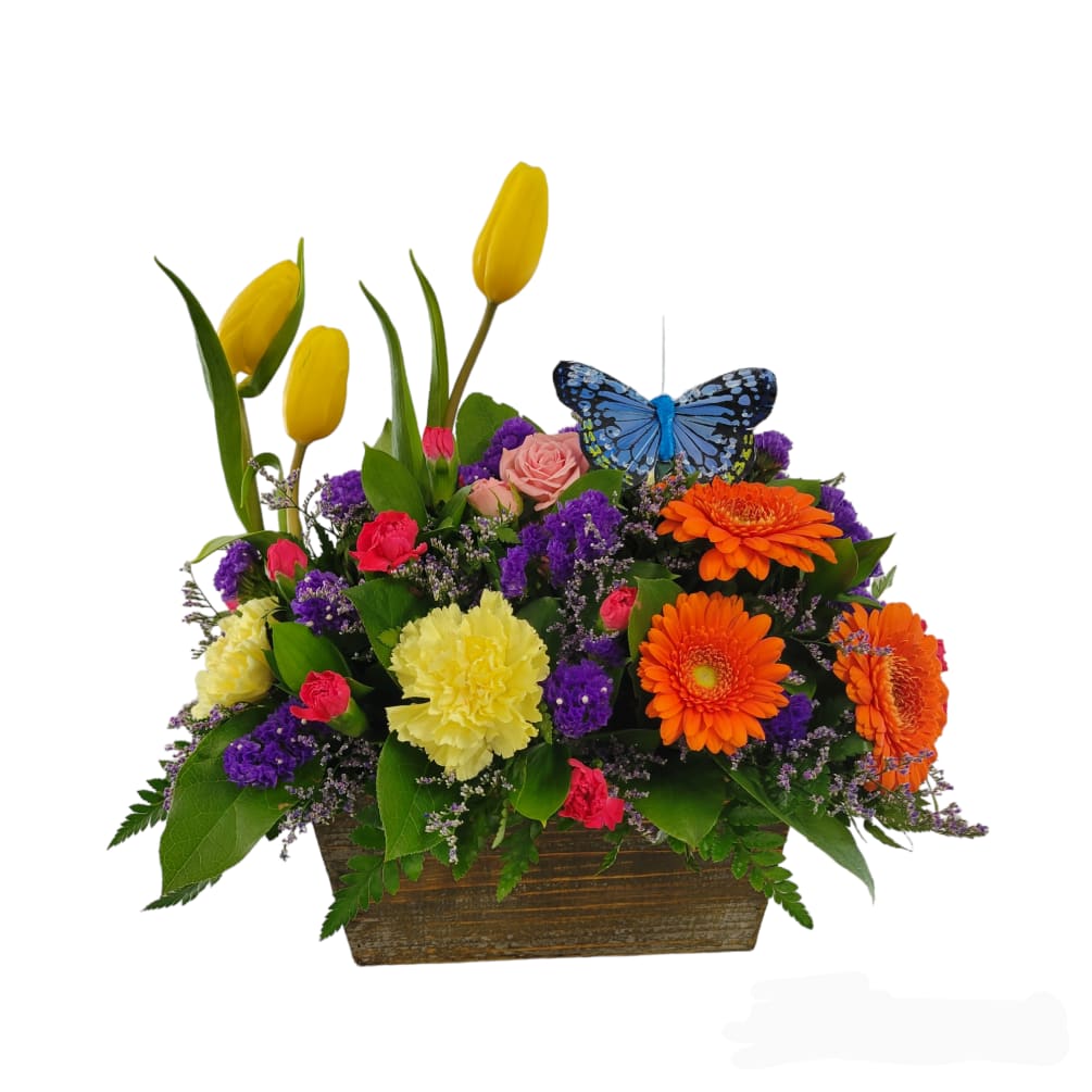 A bright mix of spring flowers to include tulips, gerber daisies, spray