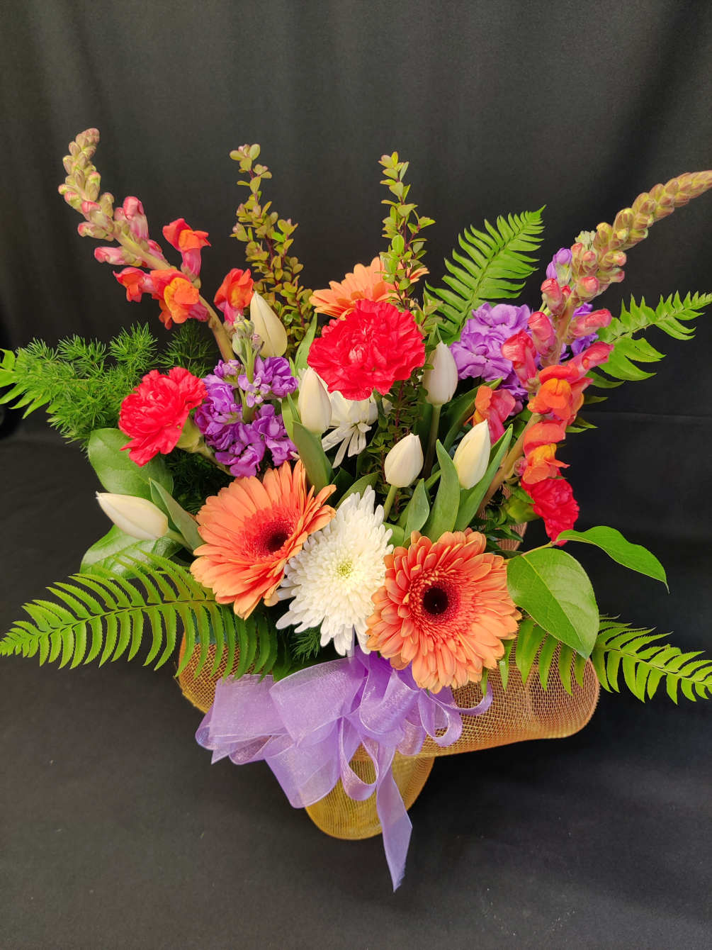 colorful assorted flowers and tulips in a wrapped vase.  Colors and