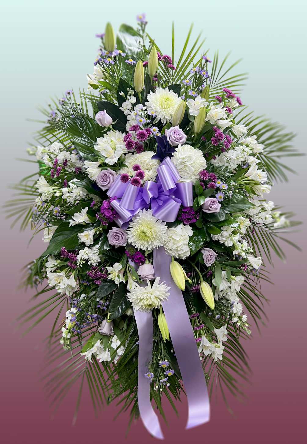 This easel spray is composed of lavender roses, mums, oriental lilies, dianthus