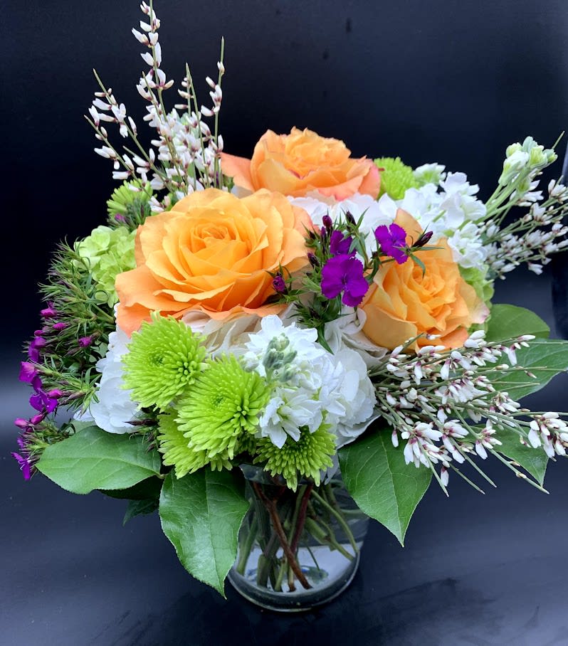 Cheerful vase filled with roses, mums and Dianthus in bright orange, green