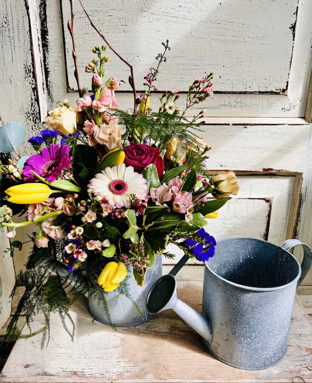 A metal watering can brimming with colorful spring blooms is a great