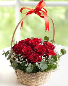 Dozen red roses in a basket filled with greenery and baby breath.