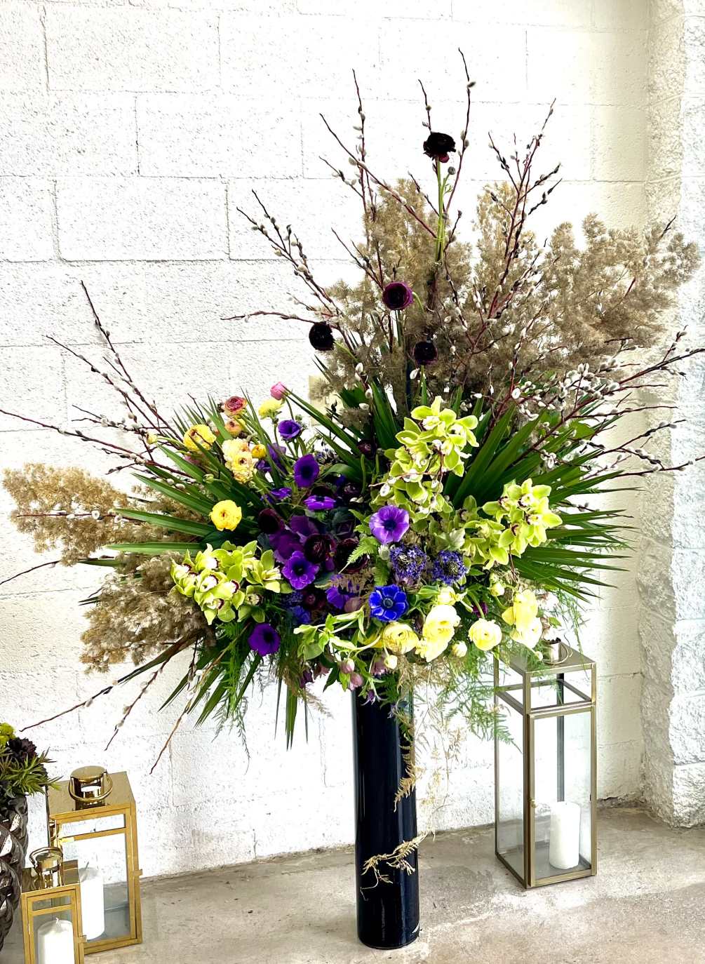 A large, wild arrangement of assorted flowers and greens that sits atop