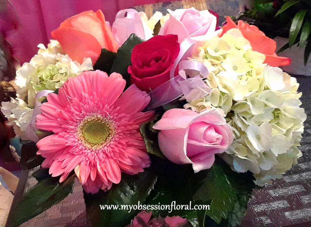 Hydrangea, roses, and gerber daisies arranged compact and low in a short