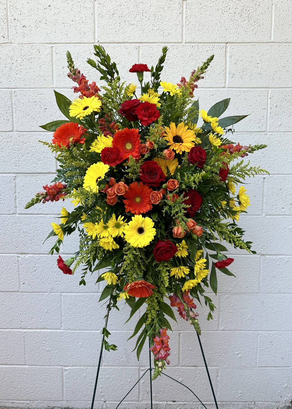 Bright warm colors perfectly arranged blooms in standing spray. Funeral/Celebration of Life
