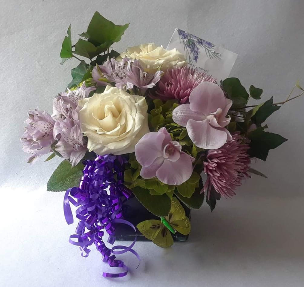 Beautiful purple blossoms of that day roses orchids and more arranged in