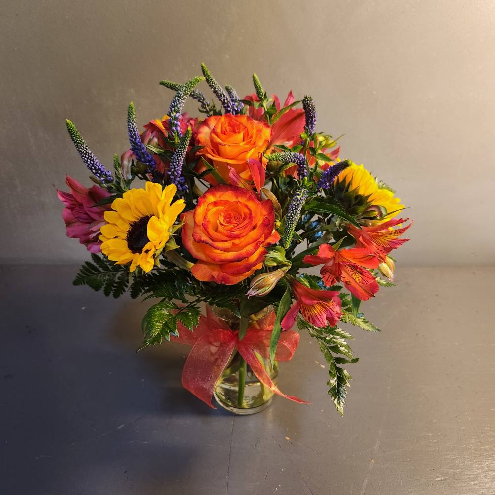 A warm, and inviting arrangement, with a beautiful mix of colorful florals