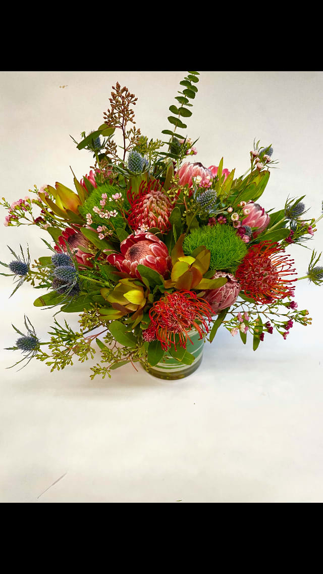 This long lasting arrangement features protea, pincushion, dianthus, wax flower, eucalyptus, thistles