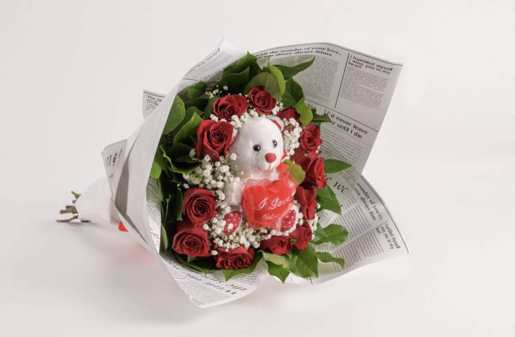 A Dozen red long stem roses with a teddy bear in the