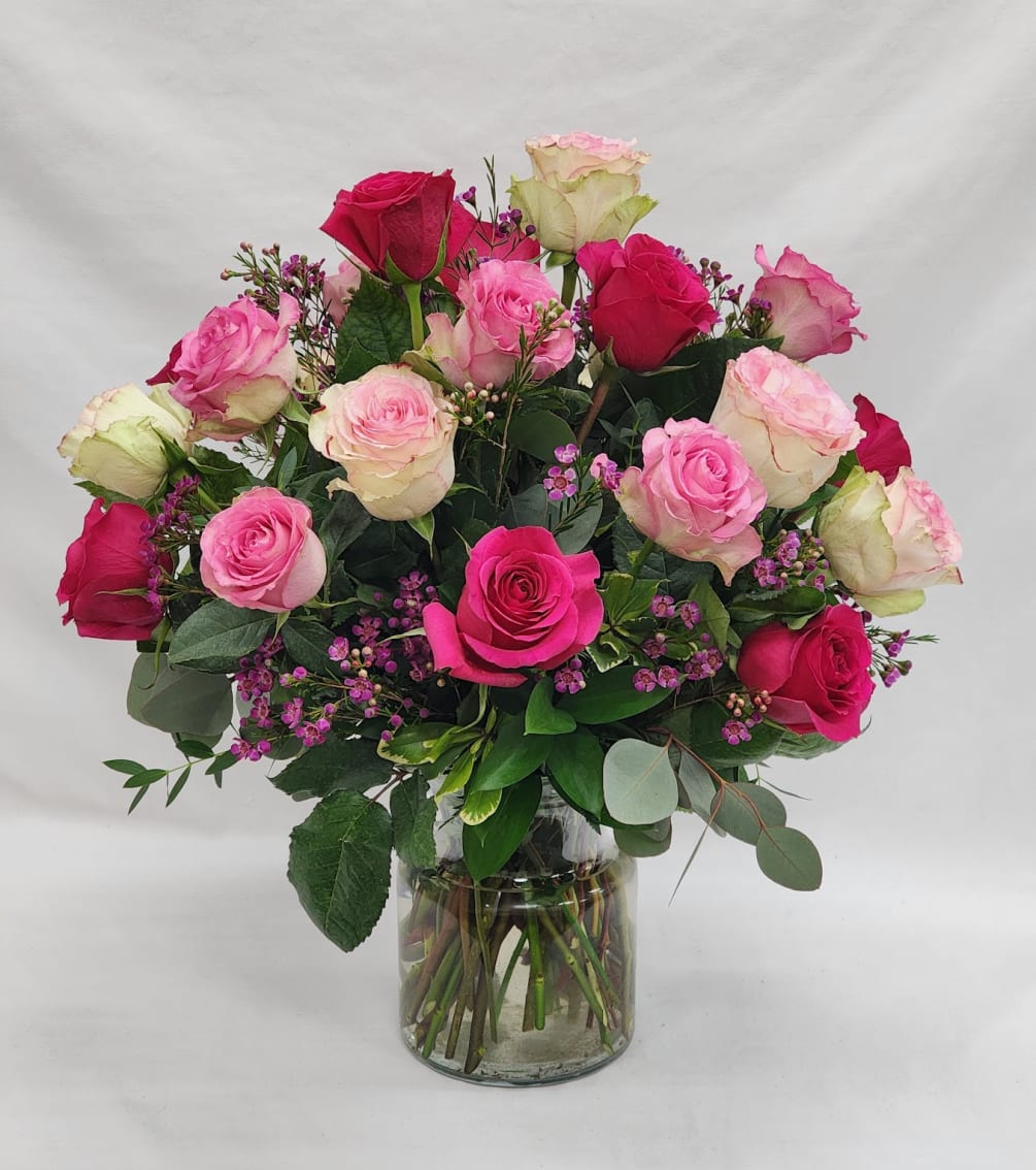 24 medium stem roses of mixed pink colors in a vase with