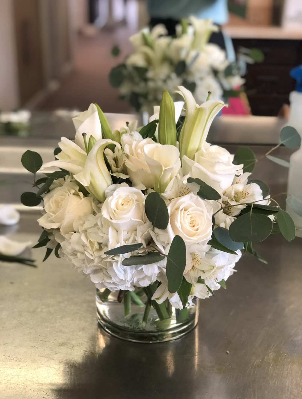 All white flowers in a cylinder vase 
roses, lilies, hydrangeas