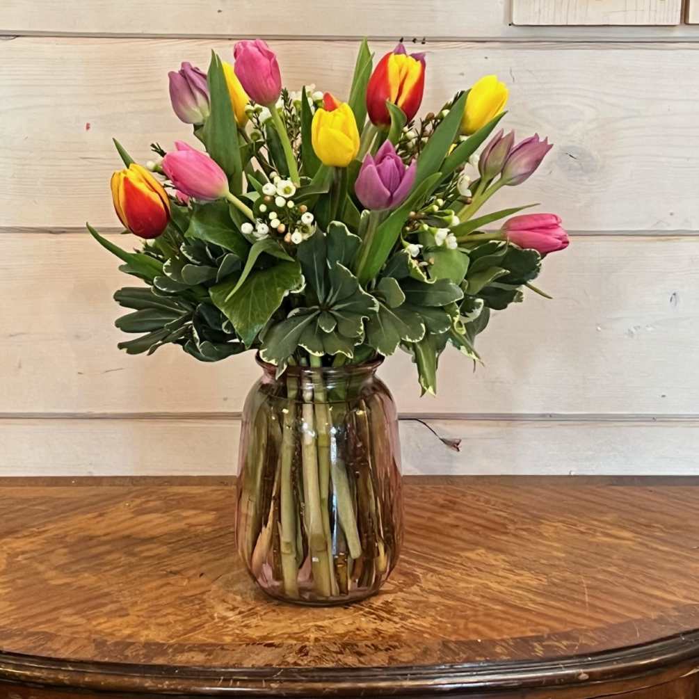 colorful spring mix of 15 tulips arranged in pink glass vase with