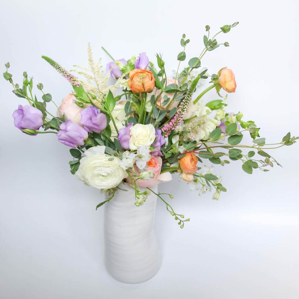 A lovely arrangement of pastel and peach flowers displayed in a vase.
