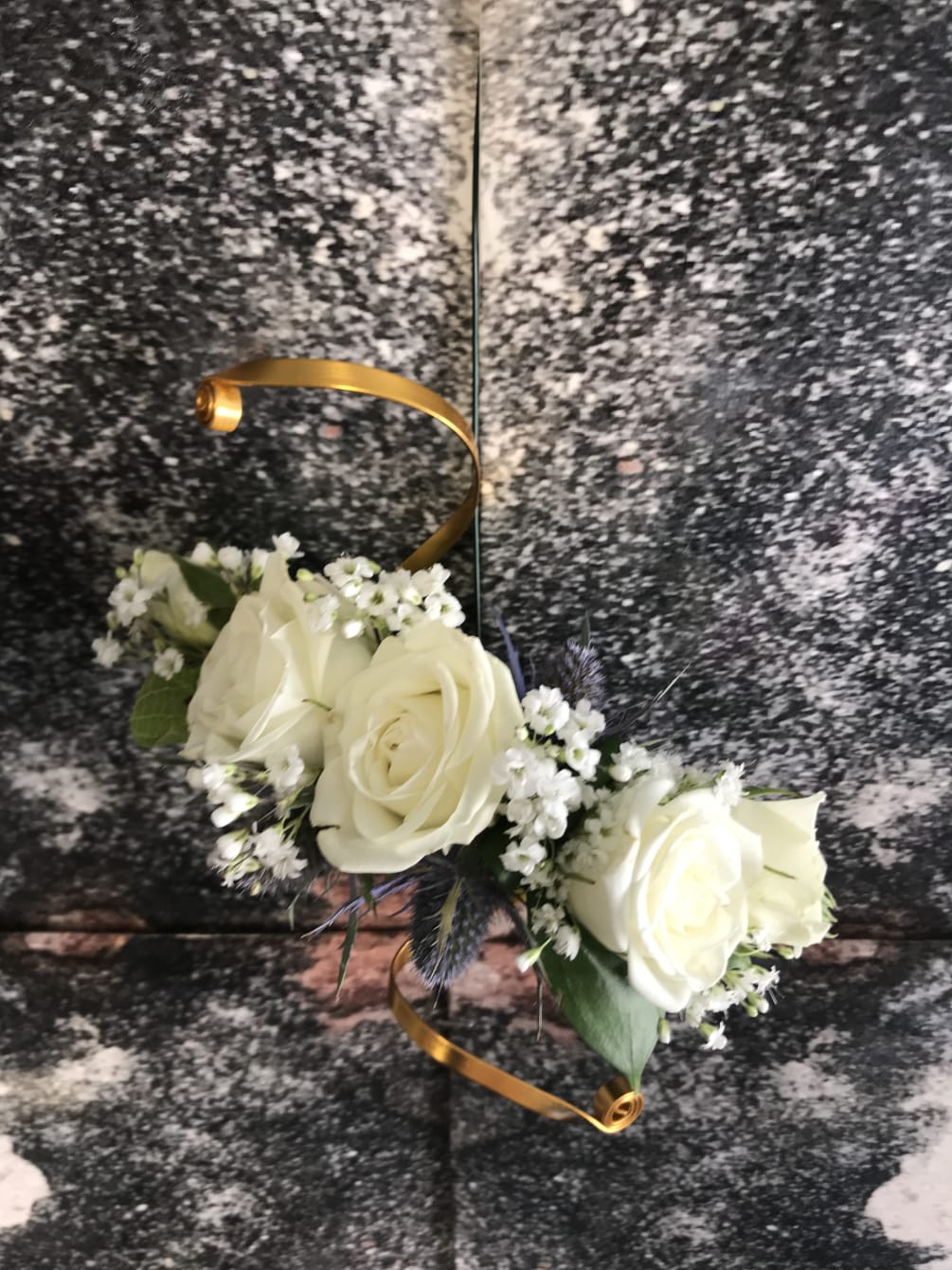 This corsage is designed with White Spray Roses, Varigated Grass and Seeded