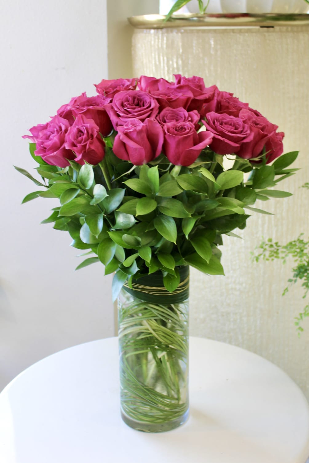 24 purple-toned roses are designed all around in this classic rose arrangement.