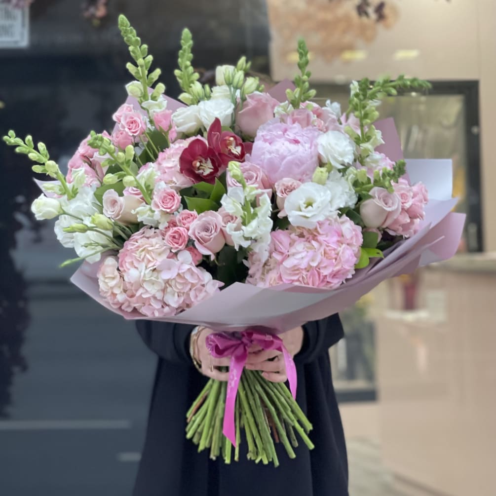 Pink light color bouquet with peonies, roses, Lisianthus, snap dragon, and orchids.