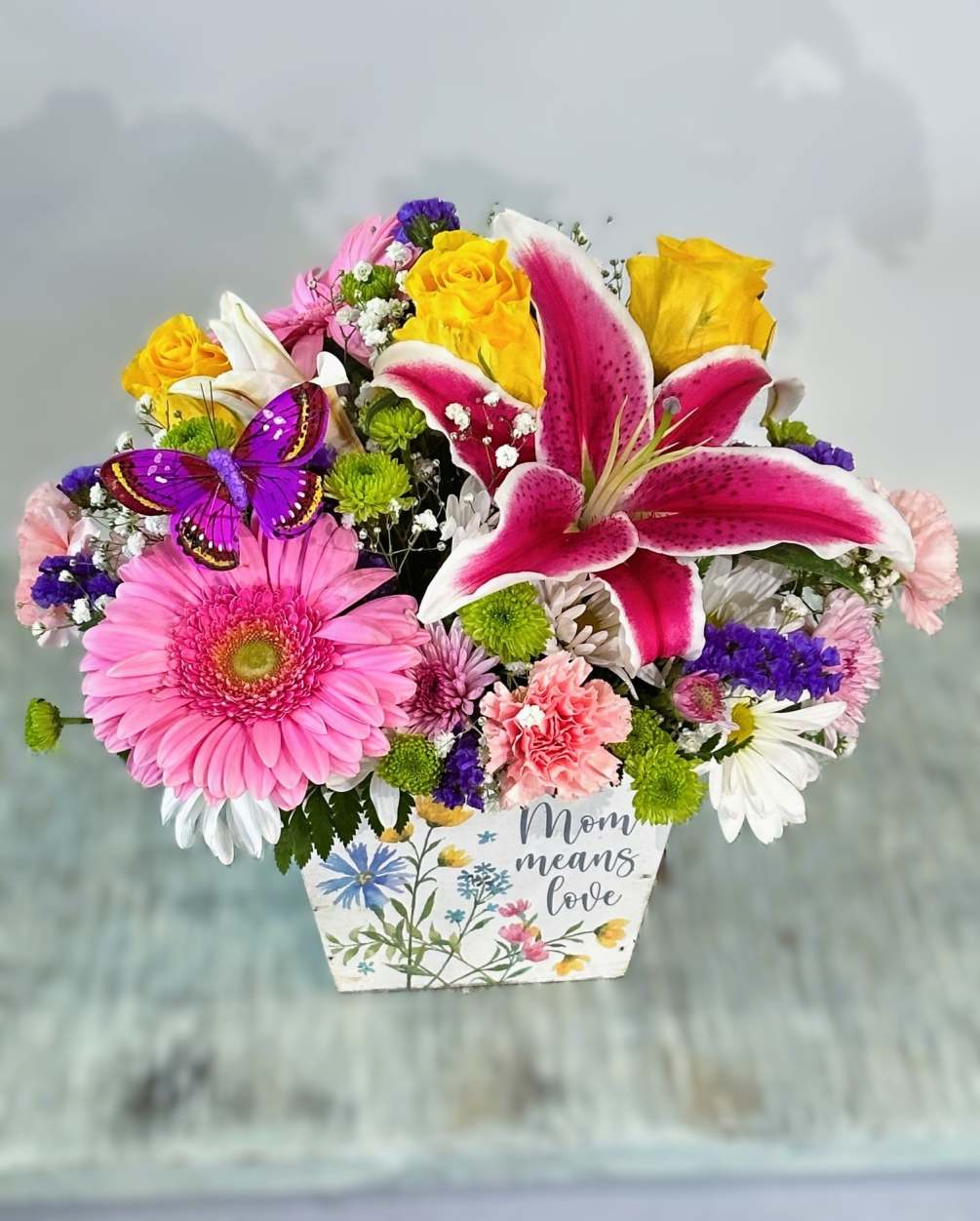 Arrangement designed in a wooden planter with a wildflower design in the