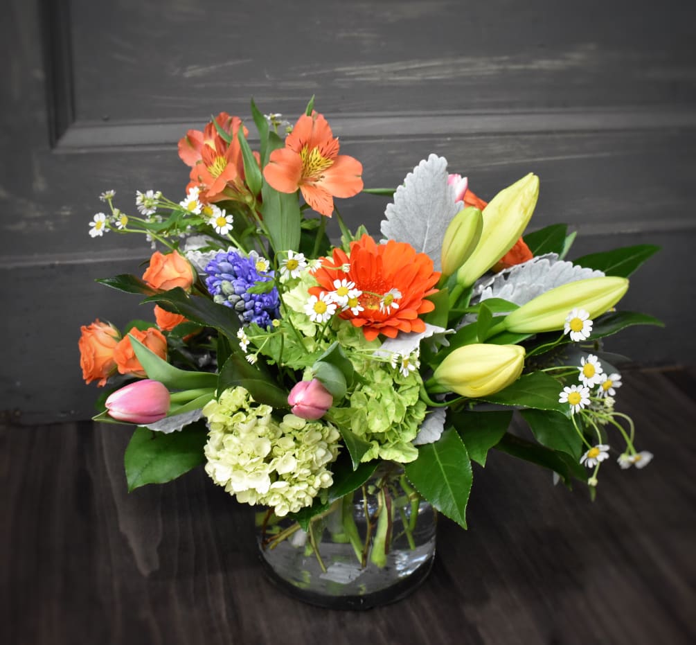 A vased bouquet full of colorful spring blooms, perfect size for coffee