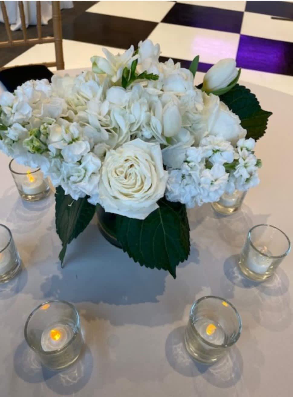 White Roses, White Stock and White Tulips in a beautiful compact arrangement.
