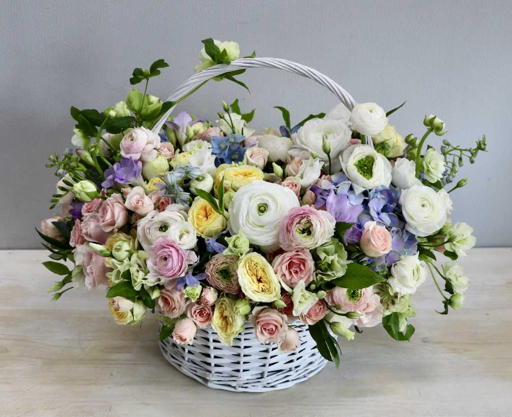 This basket is filled with variety of pastel roses and ranunculus and