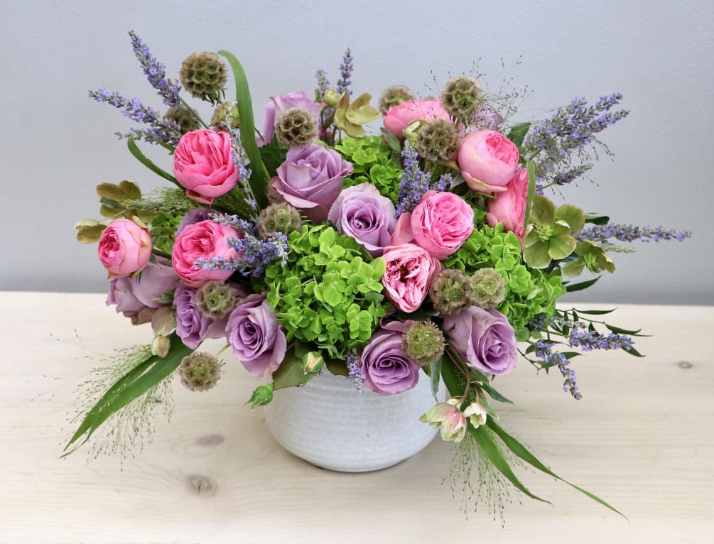 This vibrant mix of roses, lavenders, and seasonal greenery gives a new