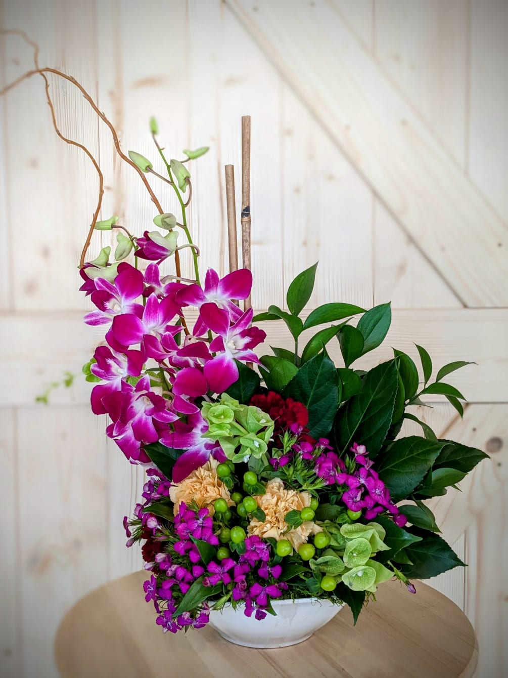 A standing foam arrangement designed with orchids, bamboo, bells of Ireland, carnations