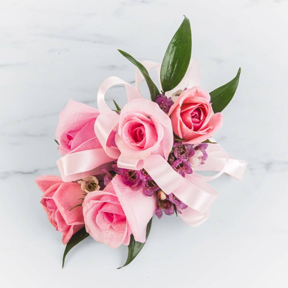 A classic pink corsage hand-tied with ribbon that compliments any outfit. A