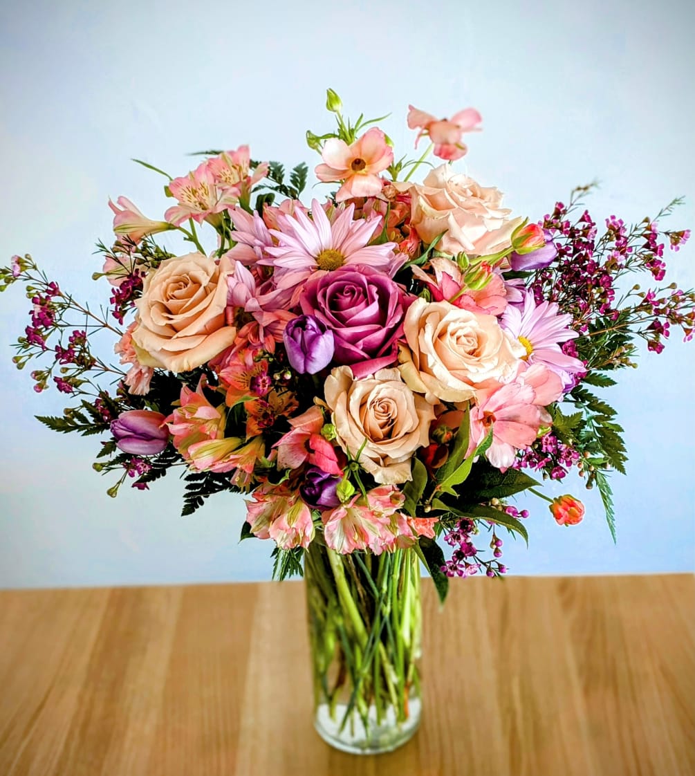 A medley of pastel blush and lavender flowers in a tall vase