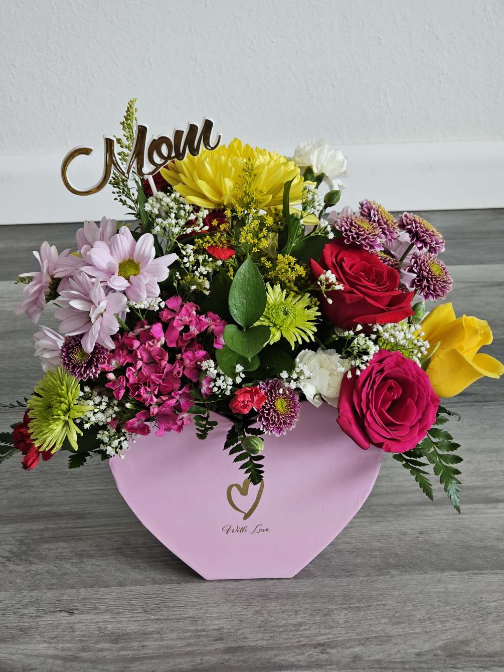 A colorful mixed arrangement designed in a pink heart box. 