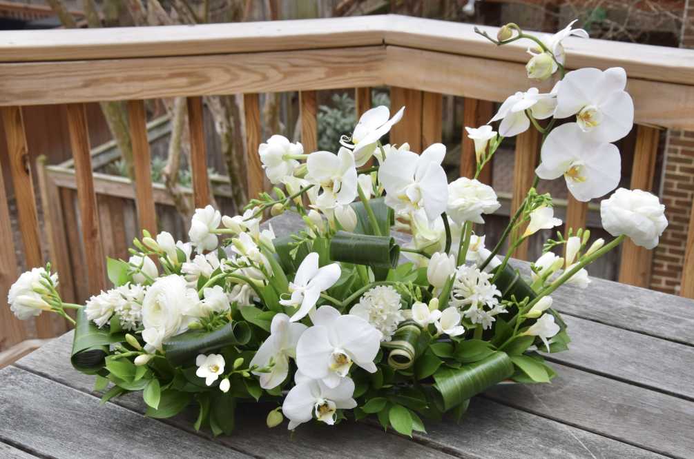 A large table flower centerpiece with premium white blooms and orchids and