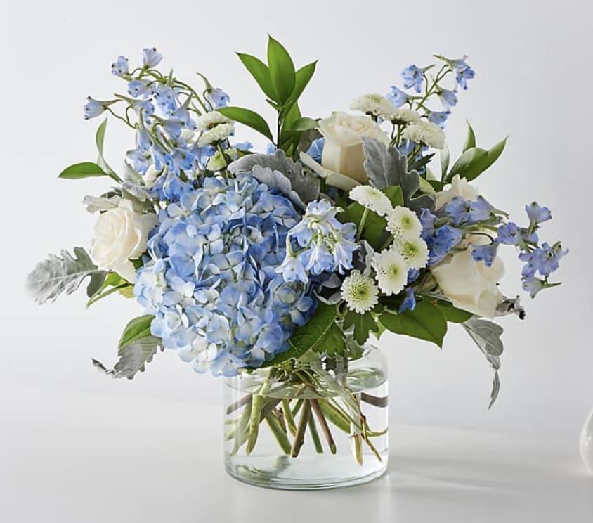 A lavish bouquet of light blue, white flowers, and lush greenery in