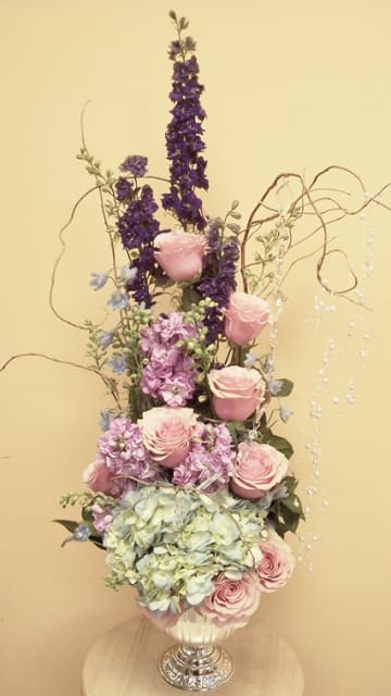 This delightful bouquet of roses, hydrangeas, purple larkspur, light pink stock, curly