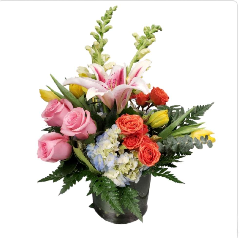 features orange roses, pink roses,  lily, snapdragons , tulips and blue