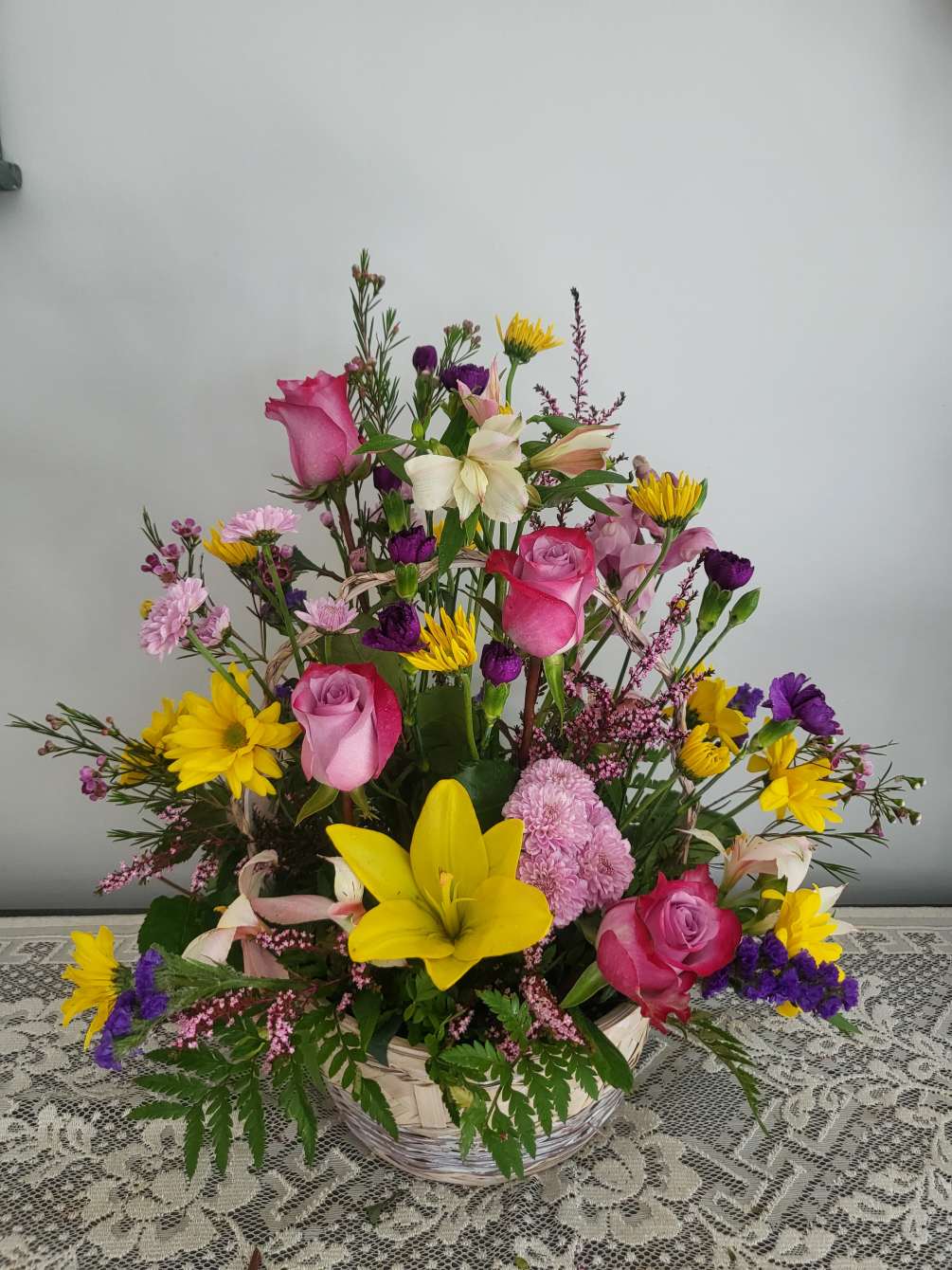 white basket of springy flowers including carnations,roses,filler  n flowers