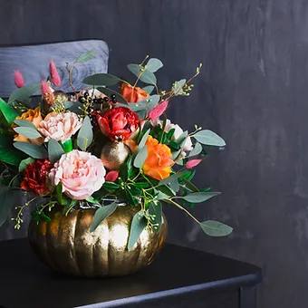 Beautiful array of fall blooms in a gleaming 11 inch golden pumpkin