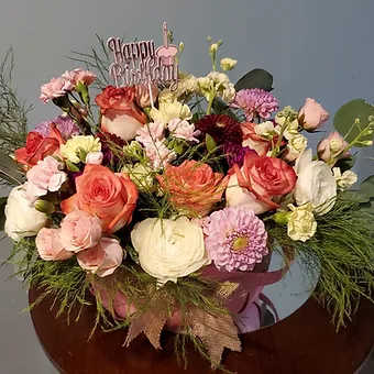 A beautiful selection of mixed flowers in a large colorful basket, perfect